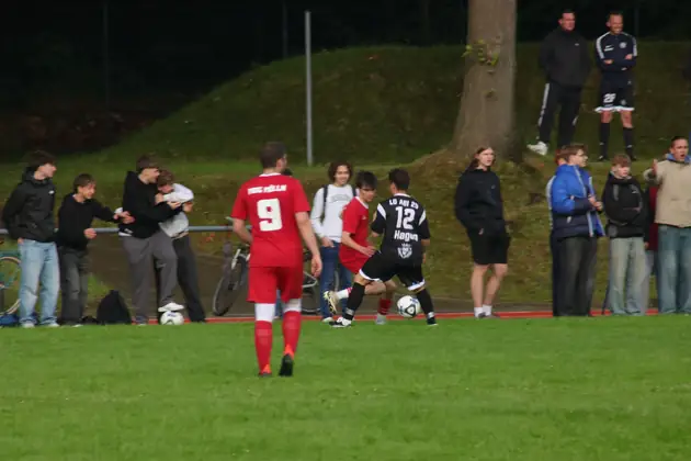 Spieler in Schwarz führt den Ball vor der Zuschauerkulisse